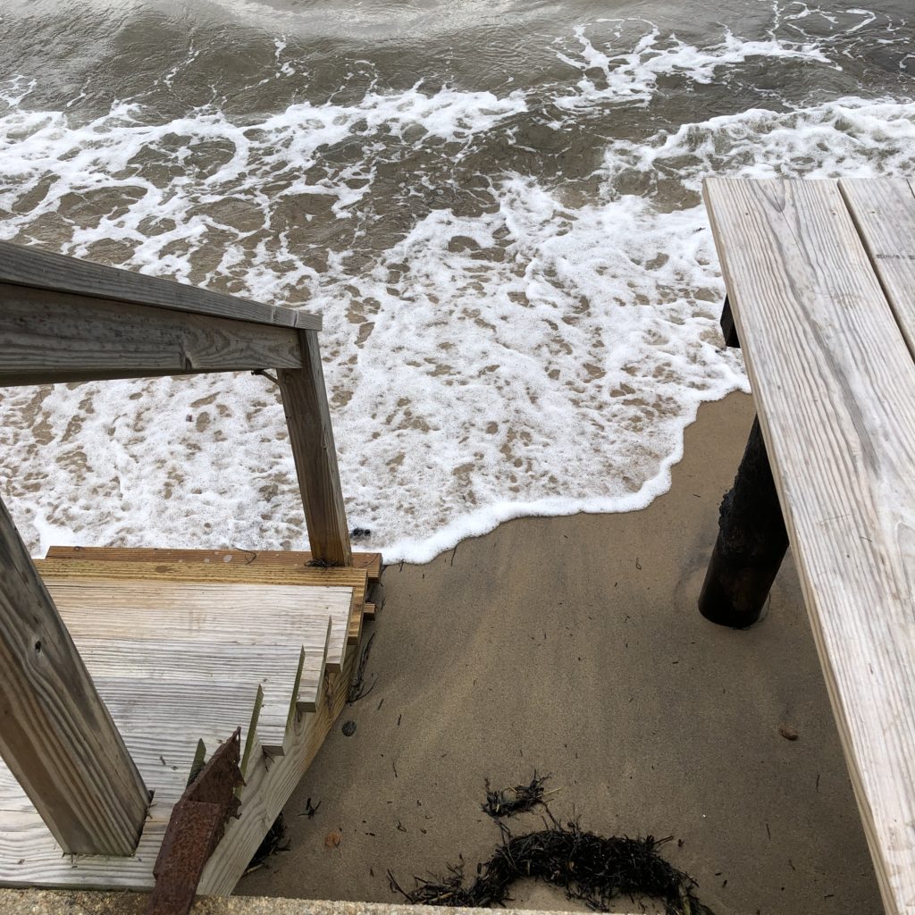 wooden steps with ocean waves at foot of stairs